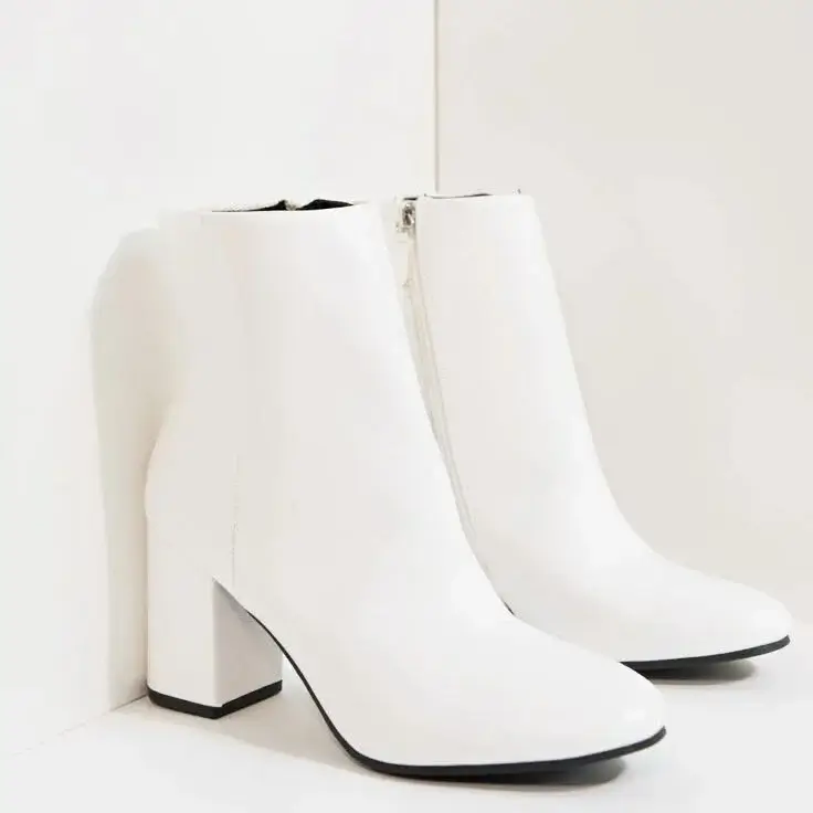 White leather ankle boots with block heels displayed against a clean white background